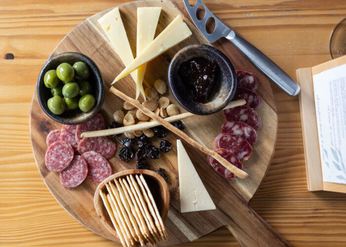 Depict image accurately for accessibility. Cheese, grapes, and charcuterie on a wooden board for wine pairing.