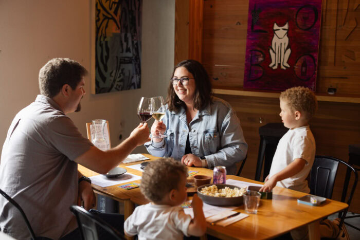 People enjoying wine tasting at Lobo Hills Wine Co., smiling and clinking glasses in a cozy, rustic setting.