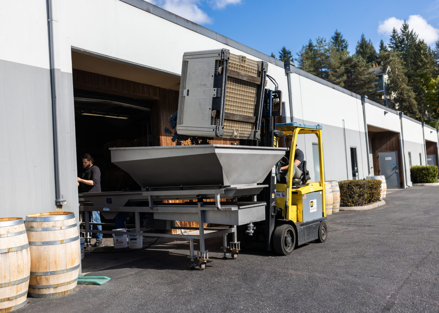 Depict image accurately for accessibility. Winery equipment being loaded onto a truck outside Lobo Hills Wine Co.
